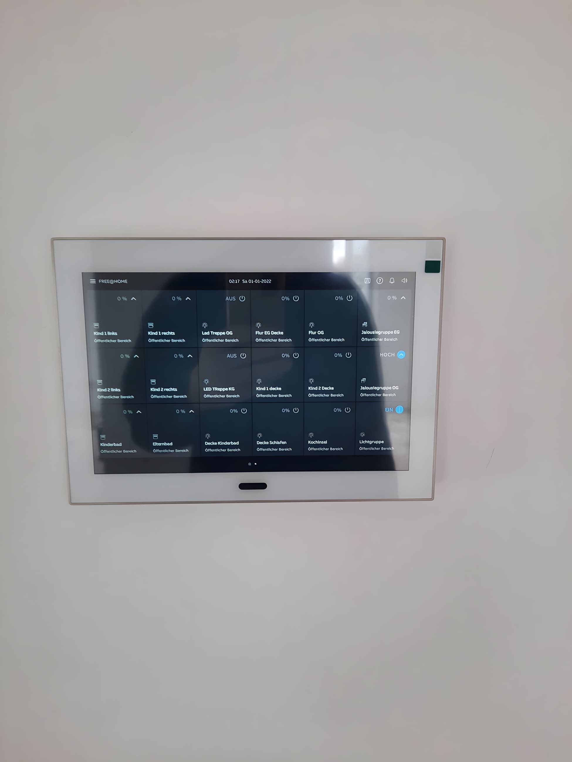 Wandbündig montiertes KNX-Touchpanel mit generischen Raumlabels für Licht- und Jalousiesteuerung